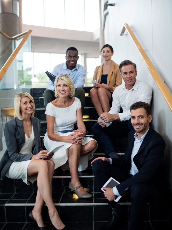 Portrait of business executives sitting on staircase at conference center