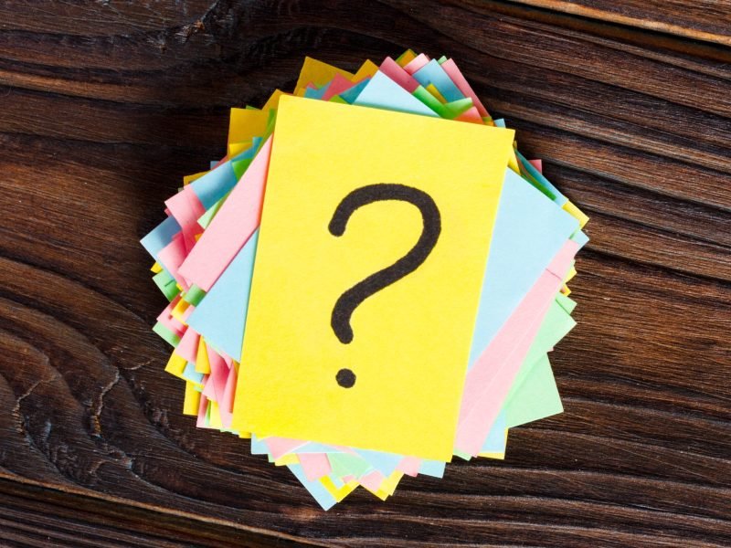 colorful question marks written reminders tickets on wooden background.