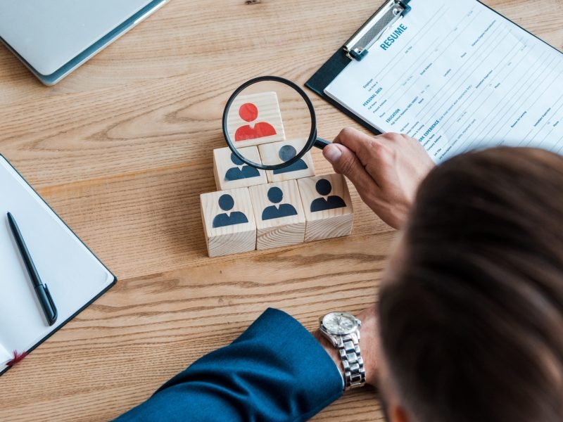 top view of man holding magnifier near wooden cubes